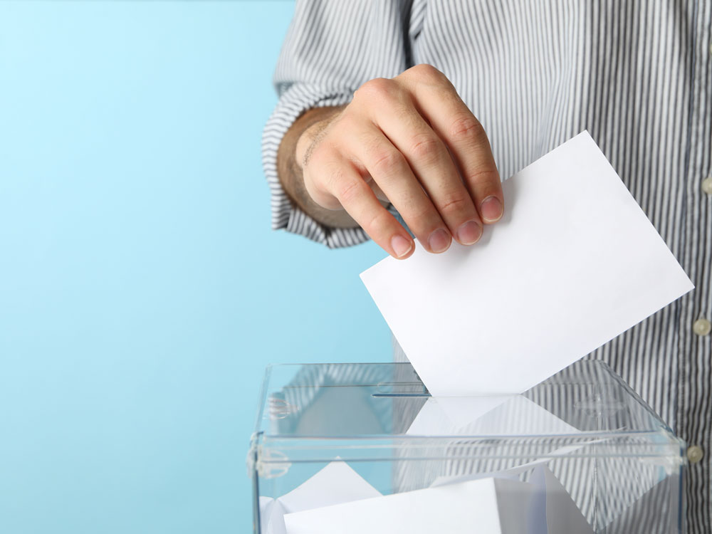 man-putting-ballot-into-voting-box